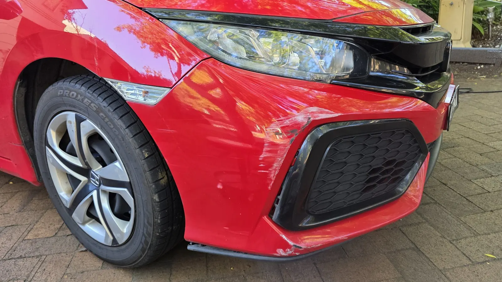 Red car bumper scuffs before repair
